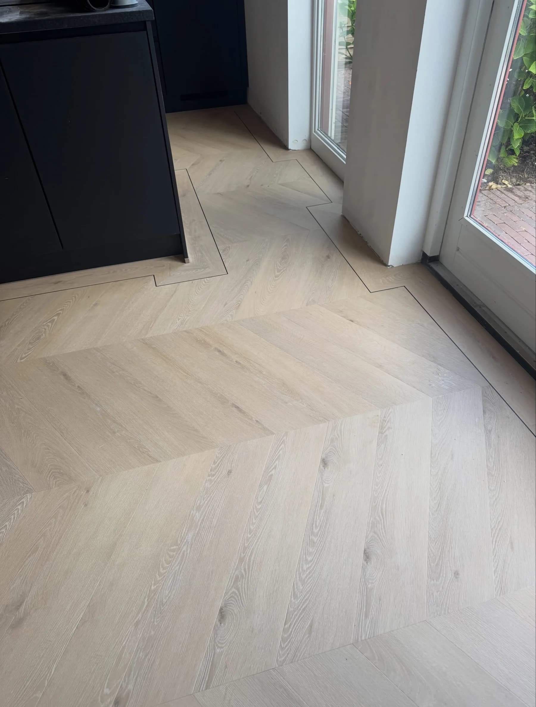 Walvisgraatvloer met een donkere bies als rand langs de wand