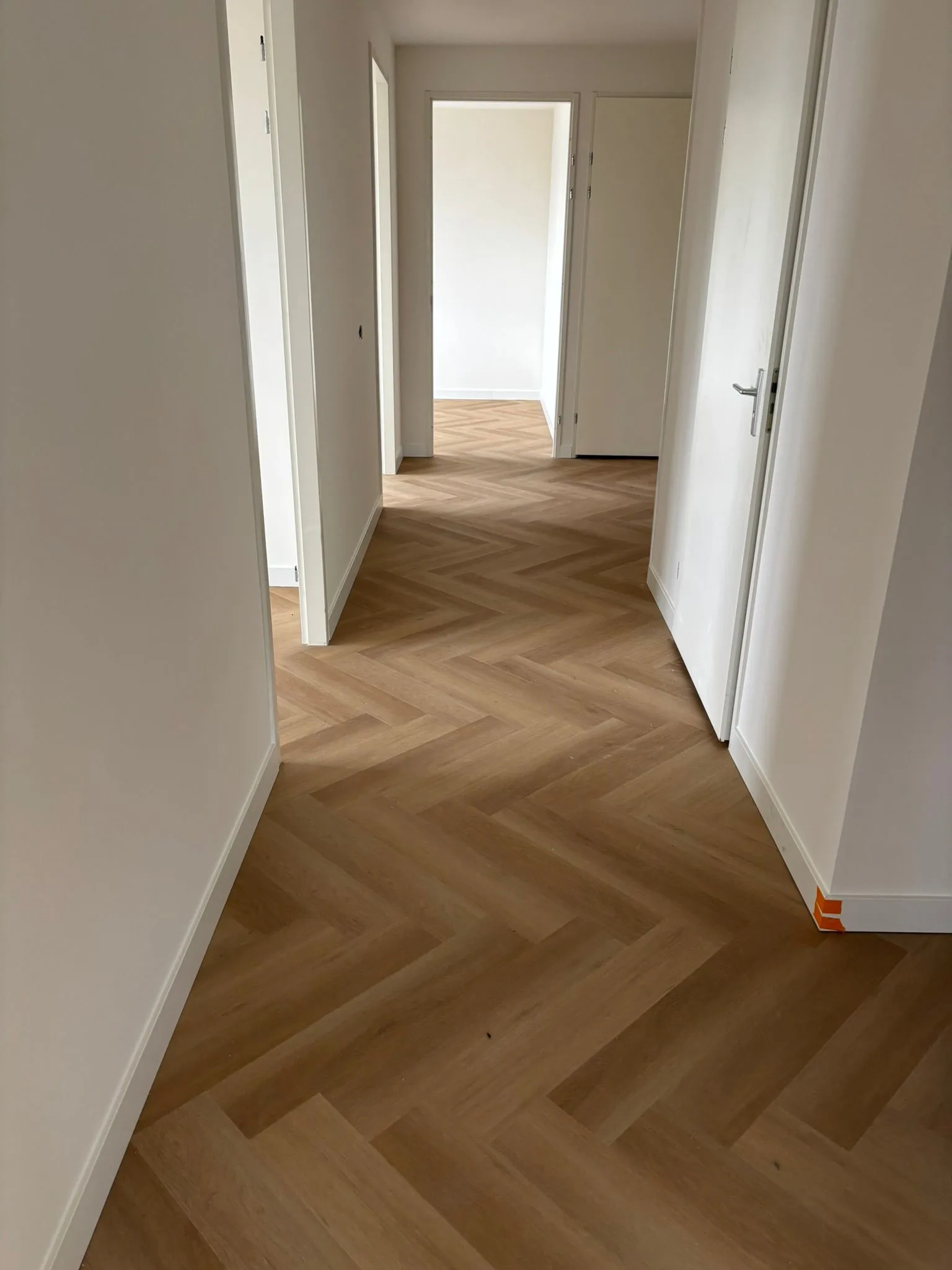 Visgraatvloer in een gang met strakke hoge plinten