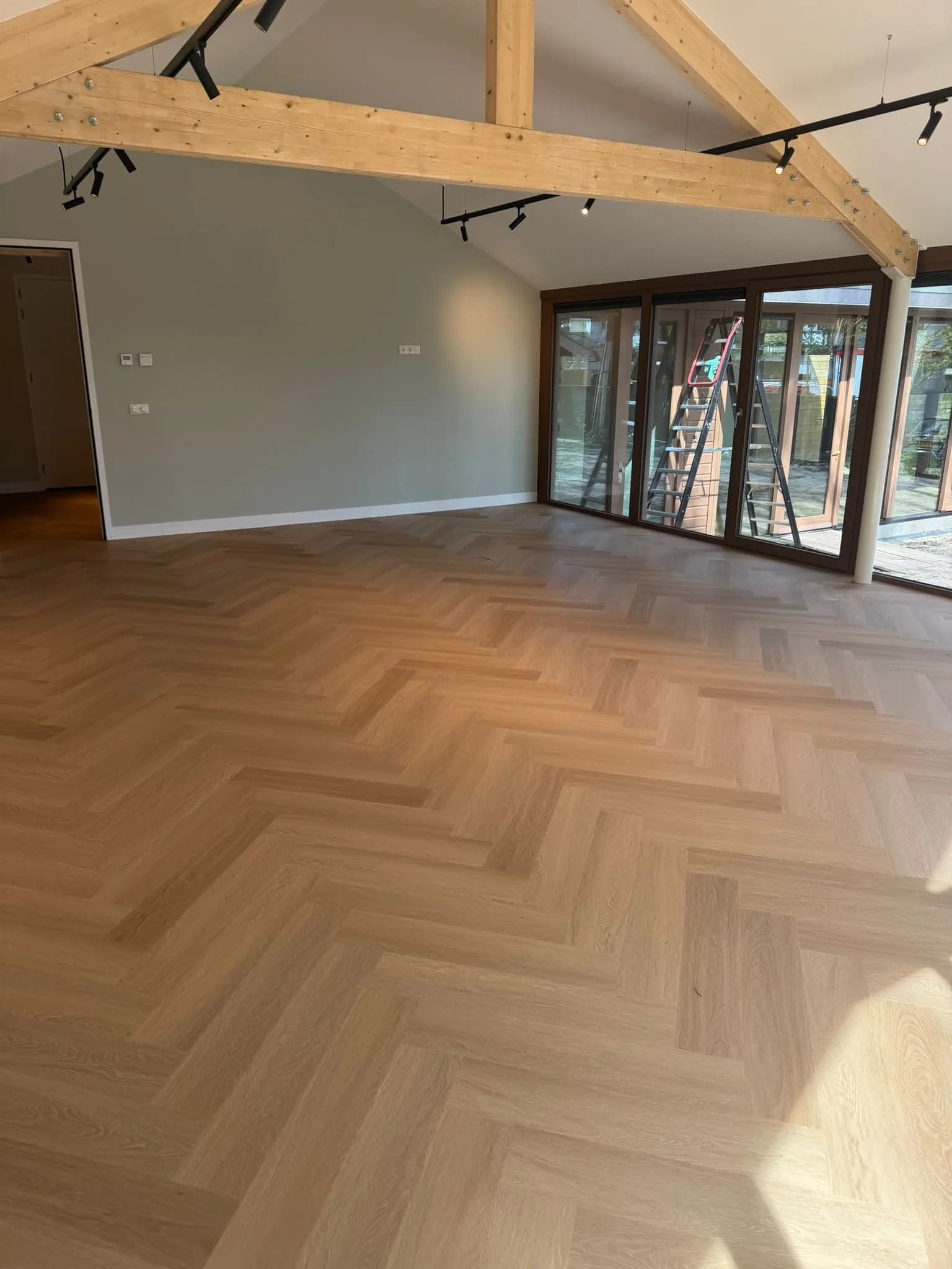 PVC visgraatvloer in een lichte woonkamer met openslaande tuindeuren