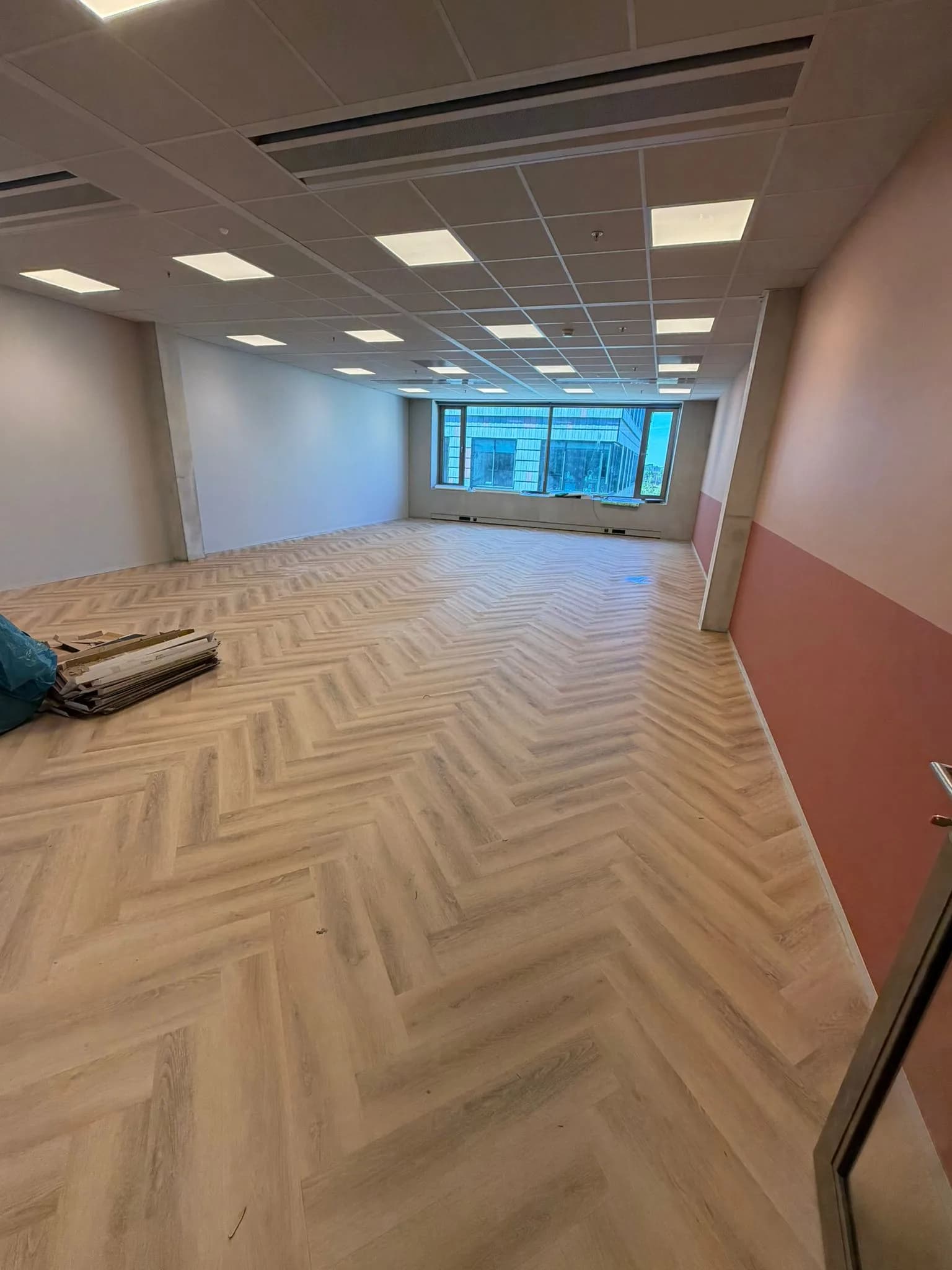 Visgraatvloer in een kantoorruimte met glaswand