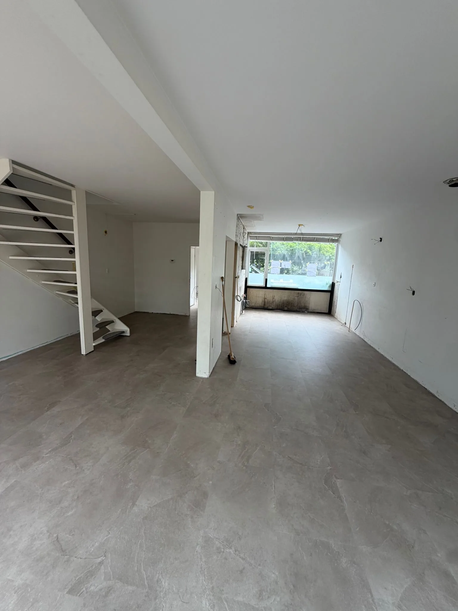 Betonlook PVC vloer in een woonkamer met open trap