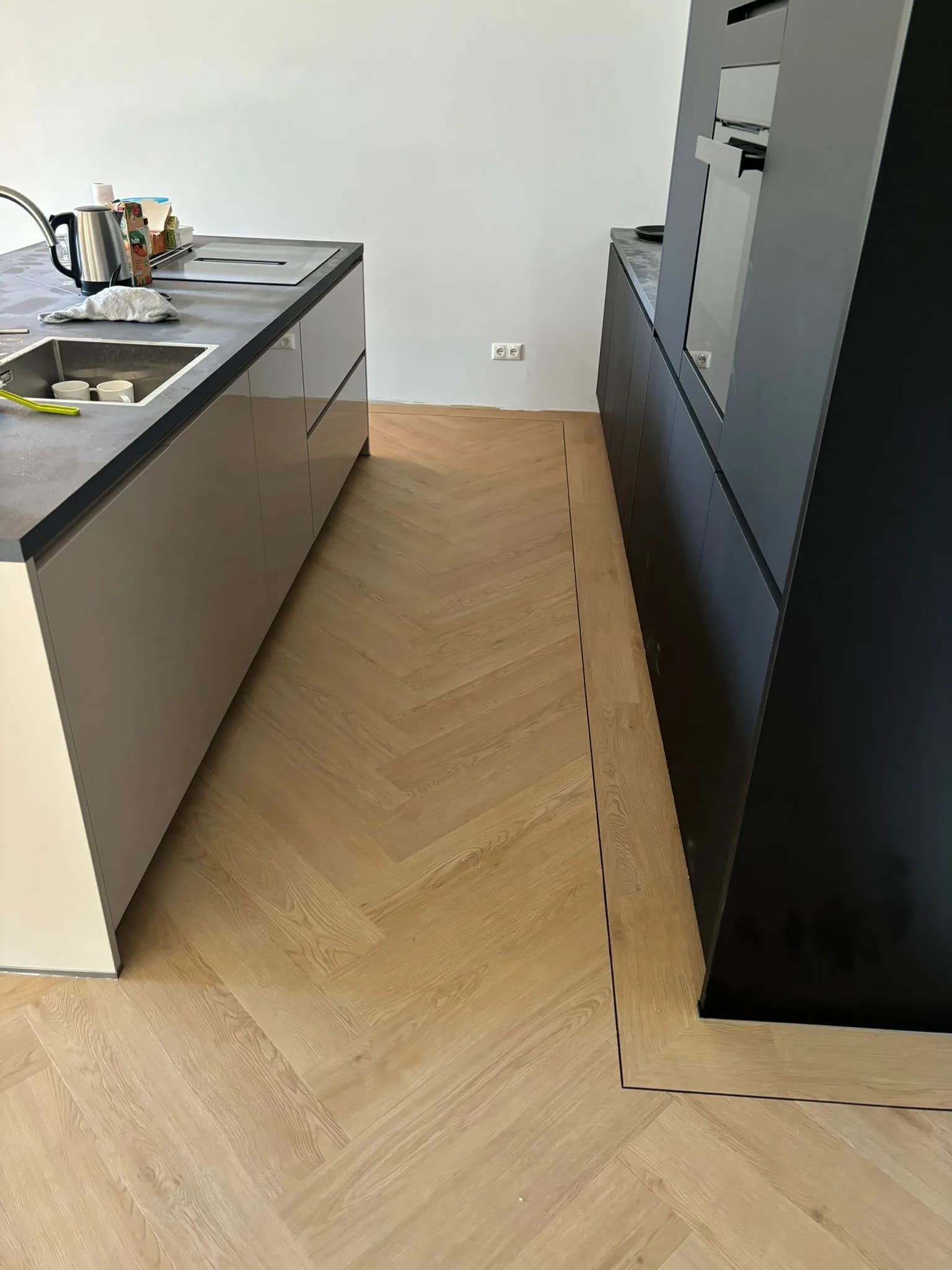 Visgraatvloer in een keuken met donker kookeiland
