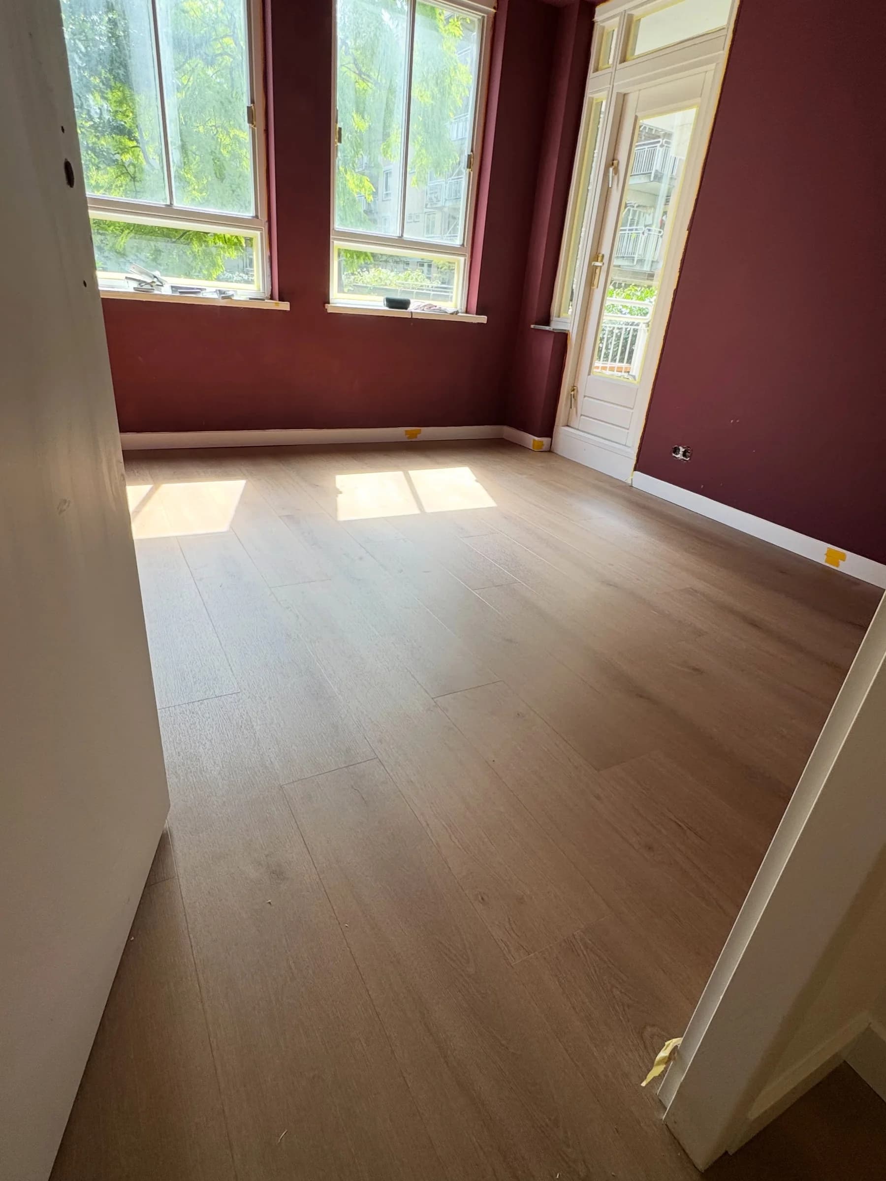 Rechte strook PVC vloer in een kamer met donkerrode wand