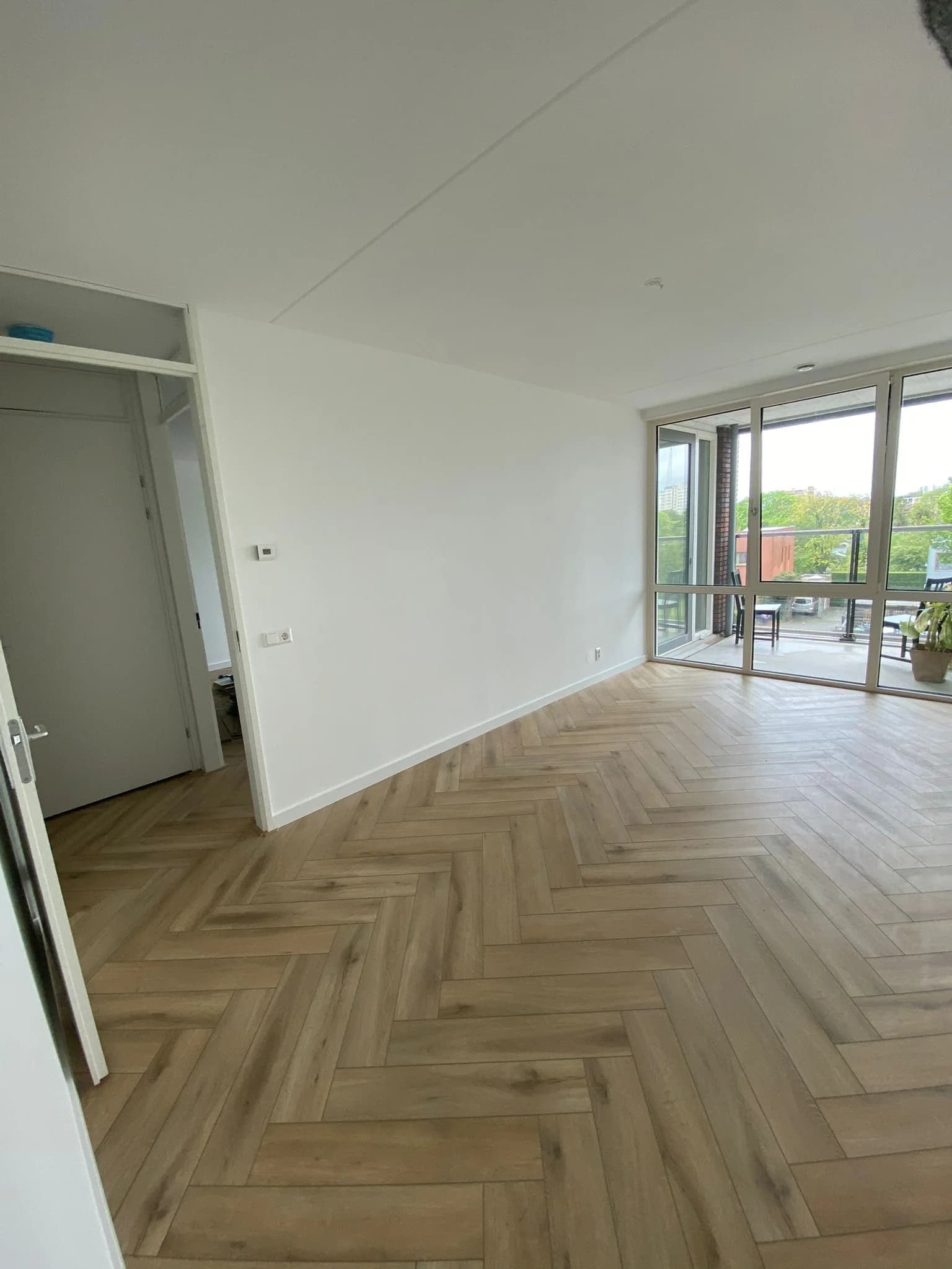 Visgraatvloer in een woonkamer met een brede raampartij naar de tuin