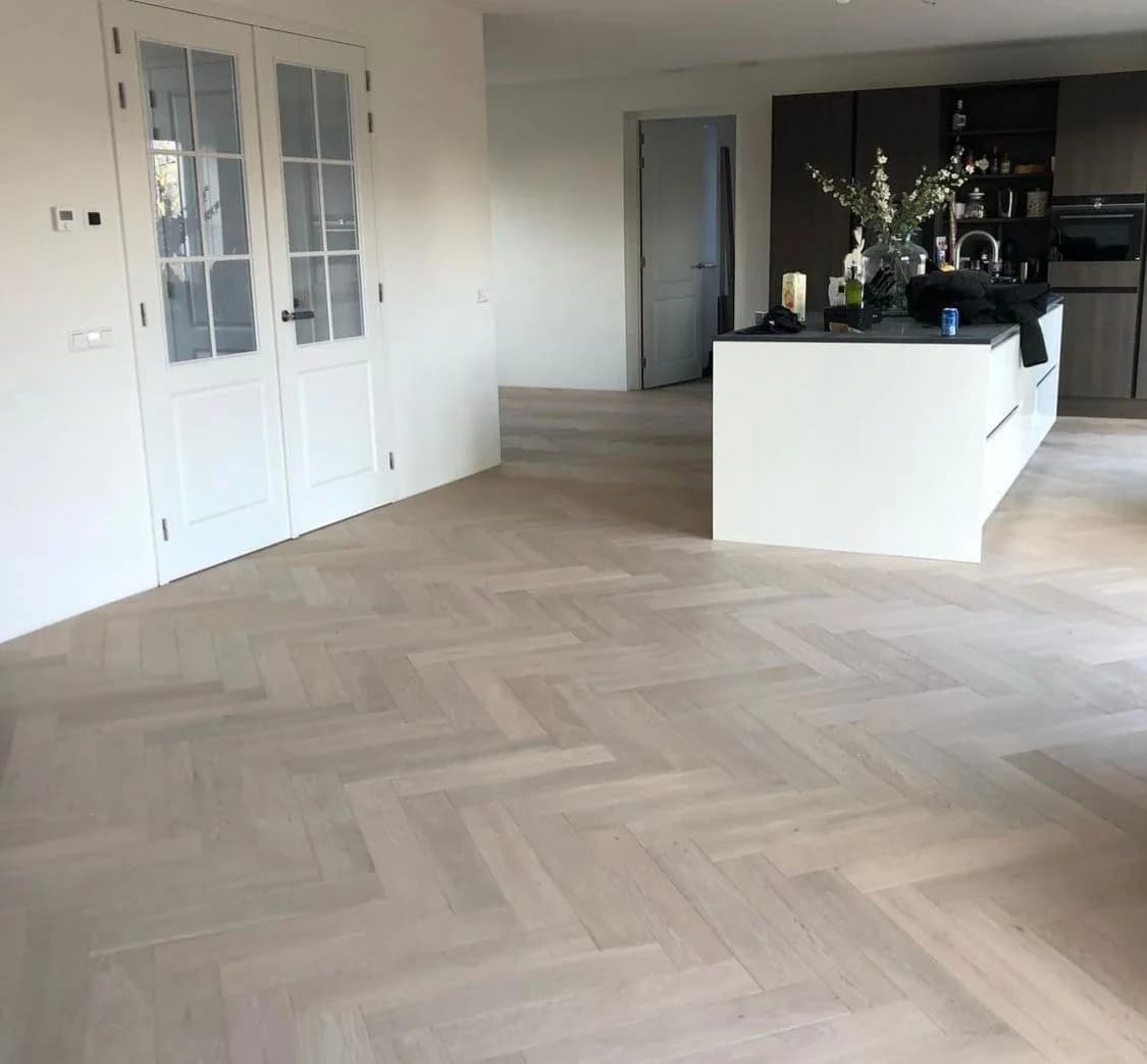Visgraatvloer in een woonkeuken met witte wanden