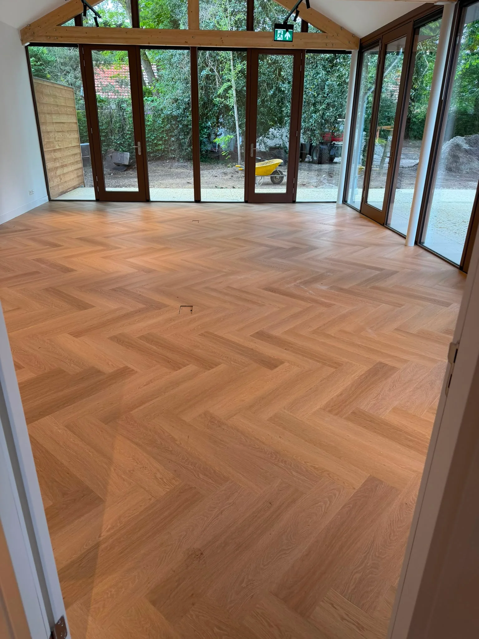 Visgraat PVC vloer in een tuinkamer met glazen puien, gelegd door Floorluxe